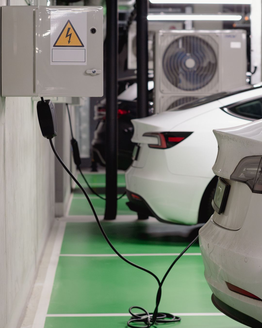 Electric vehicles charging in a car park with visible electrical infrastructure